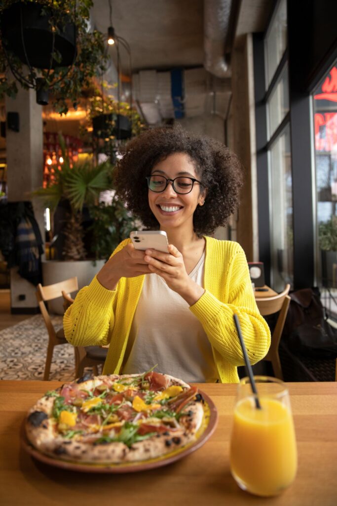 happy woman taking photo of pizza