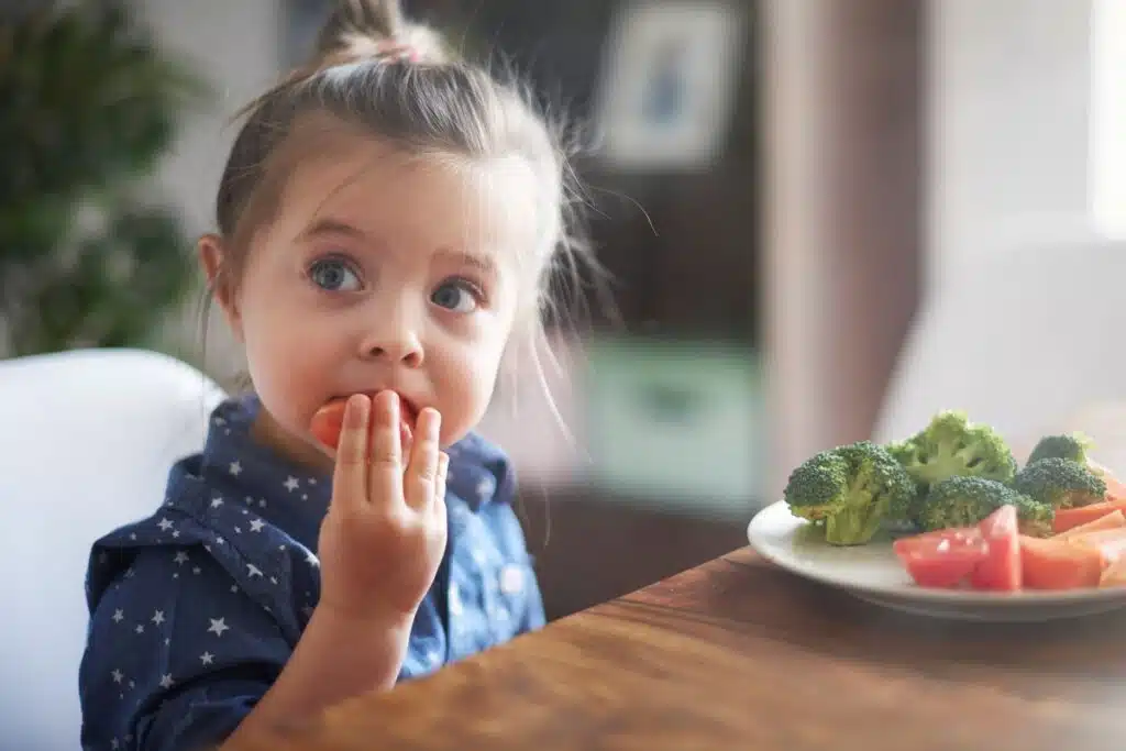 young child eating plate of vegetables