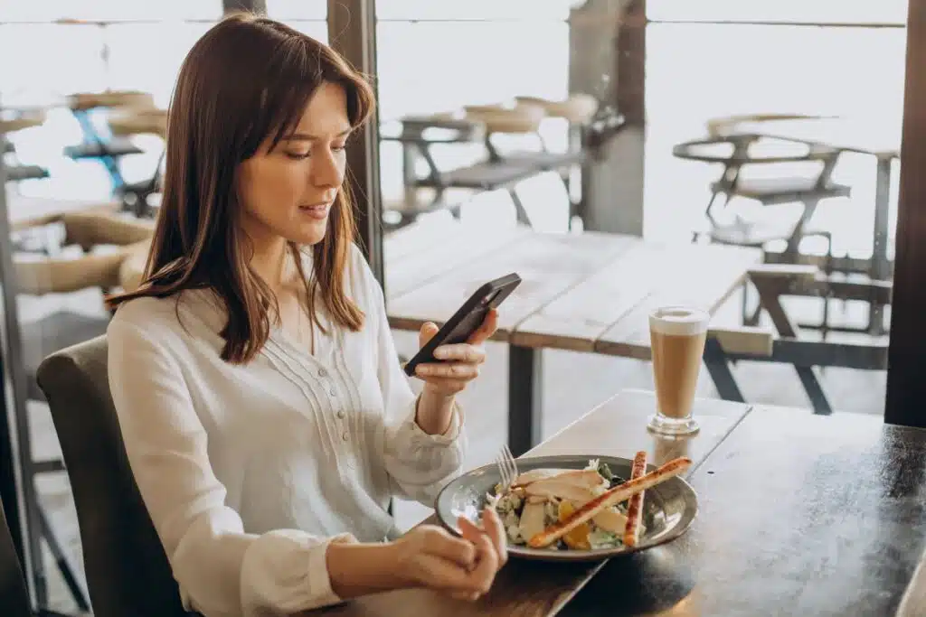 woman looking at diet app on phone while eating lunch