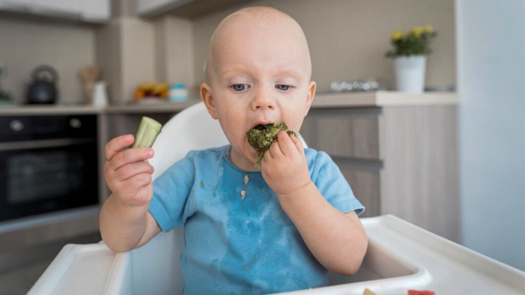 baby eating large handful of vegetables