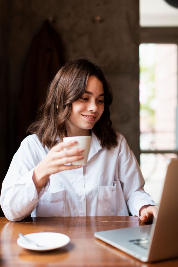 woman drinking coffee while looking at laptop
