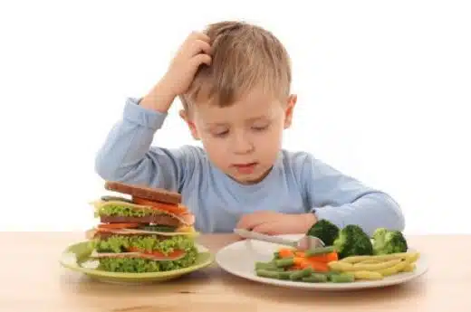 child with autism looking suspiciously at food