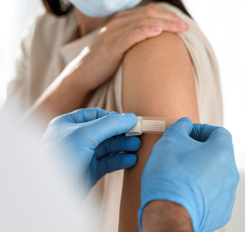 doctor putting bandaid on womans arm after injection