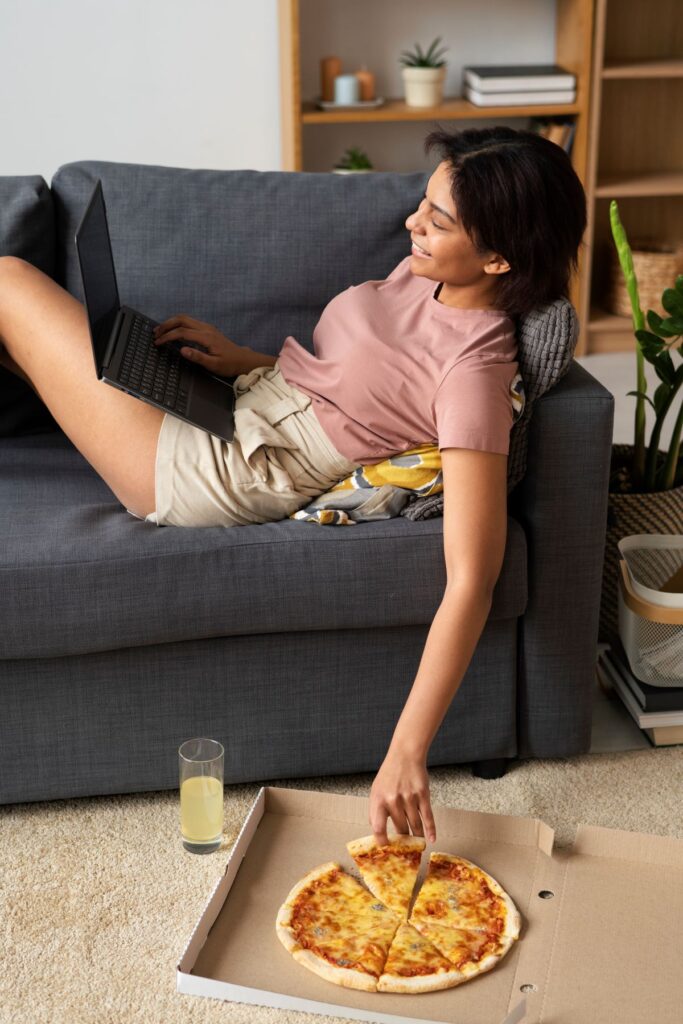woman eating a pizza on couch