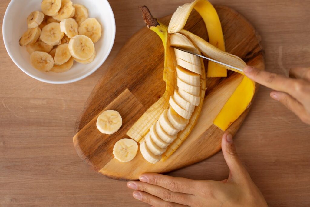 person slicing banana on cutting board