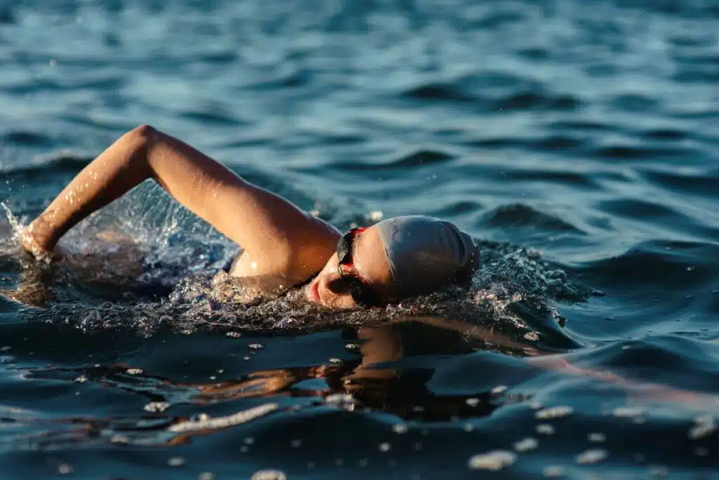 woman swimming outside with cap and googles